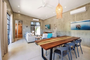 A modern living room with a dining table, sofas, and a TV.