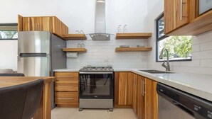 A compact kitchen with wooden cabinets, a stainless steel refrigerator, a built-in oven, and a dishwasher.
