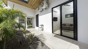 A modern interior with a glass door leading to a living area, a ceiling fan, and a small seating area with a chair.