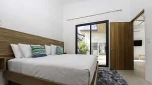 A modern bedroom with a wooden bed, white bedding, and a patterned rug.