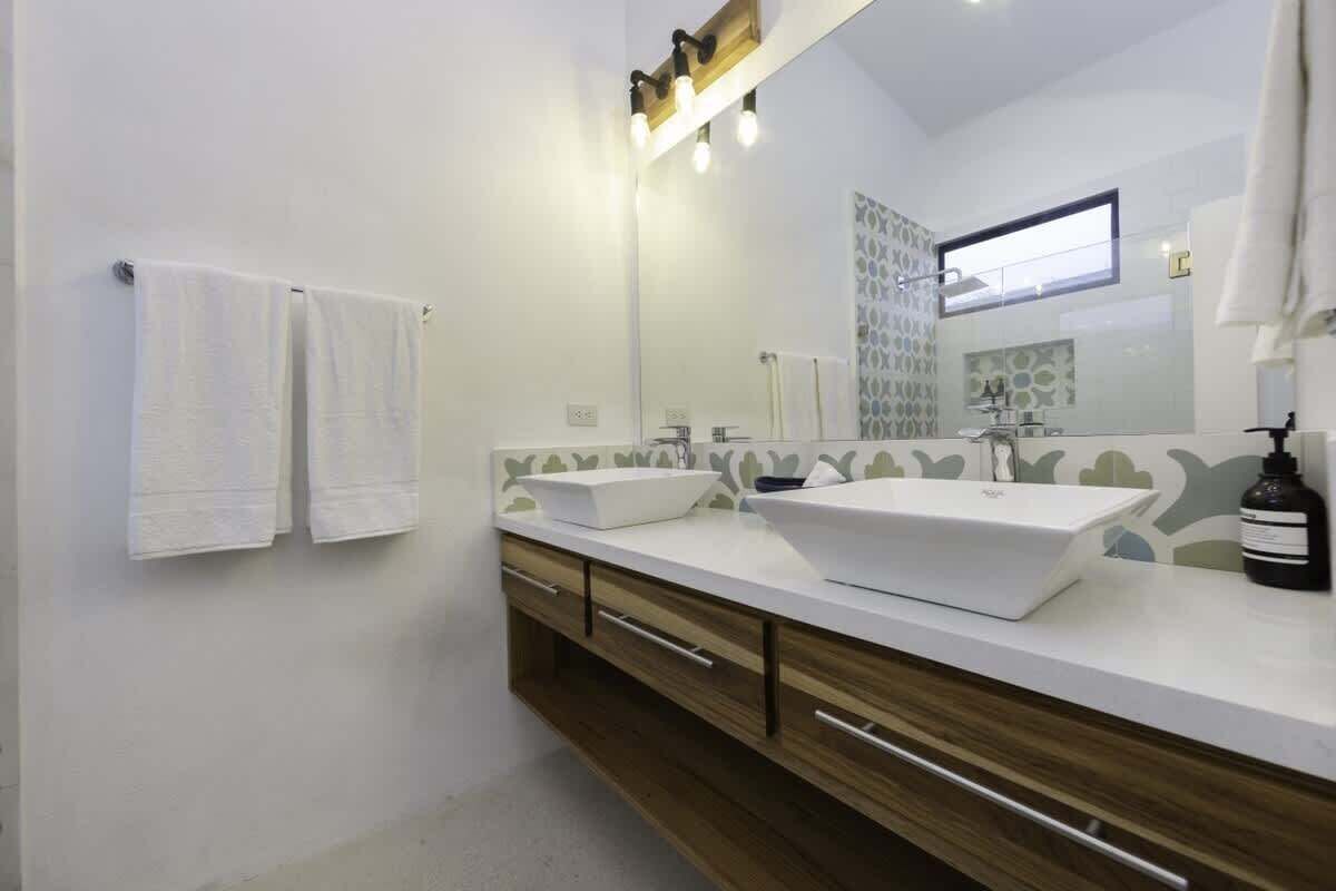 Ein modernes Badezimmer mit zwei Waschbecken, einem großen Spiegel und einem Handtuchhalter.
