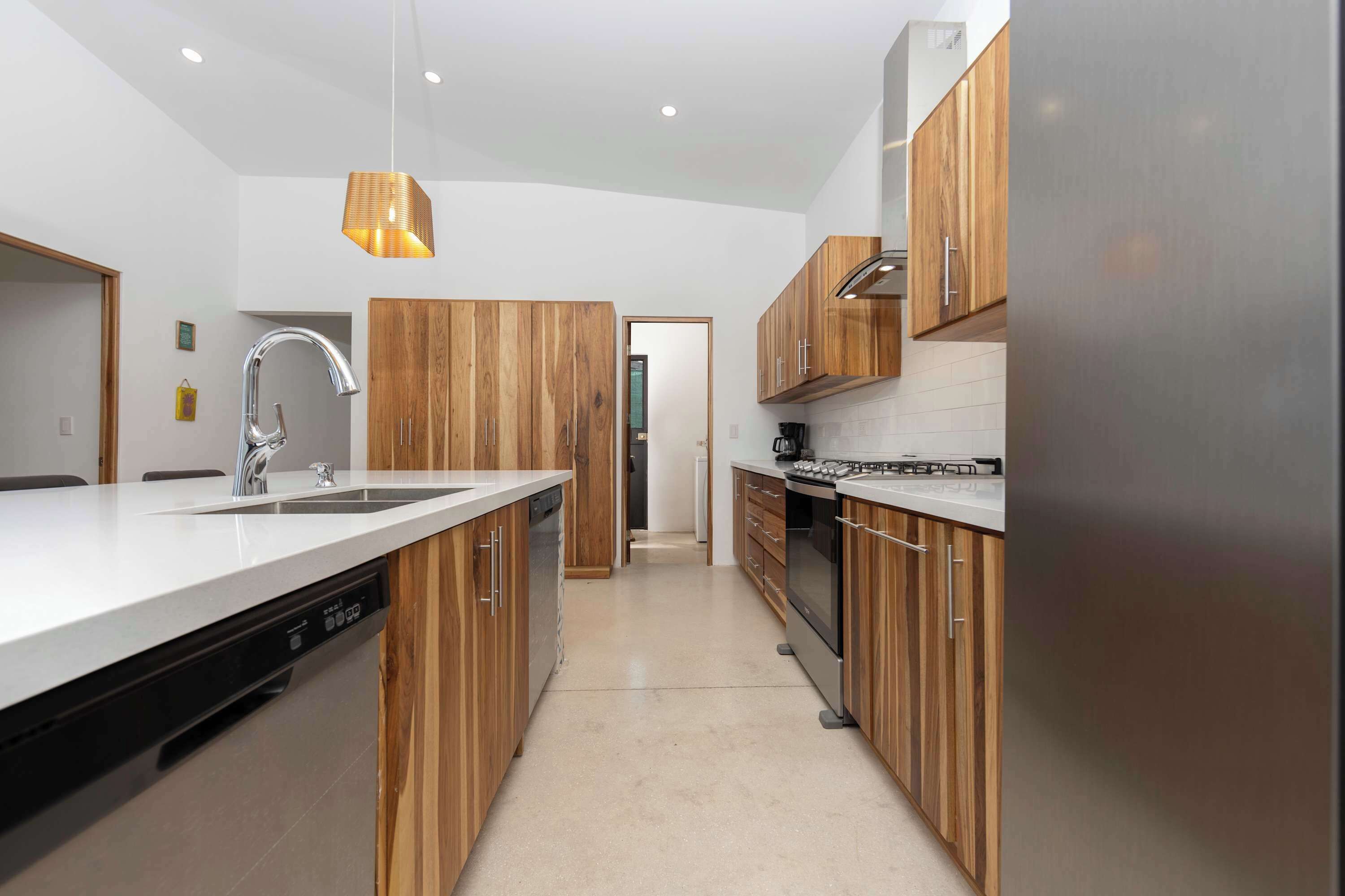 A modern kitchen with wooden cabinets, a stainless steel refrigerator, and a dishwasher.
