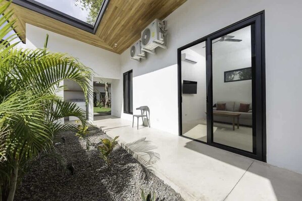 A modern interior with a large sliding glass door, a ceiling fan, and a small seating area with a chair and a table.