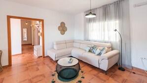 A living room with a beige sectional sofa, a round coffee table, and a floor lamp. - Casa Mati Cómpeta by Ruralidays (Málaga)