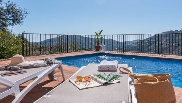 A poolside area with lounge chairs, towels, sunglasses, and a plant. - Casa Mati Cómpeta by Ruralidays (Málaga)