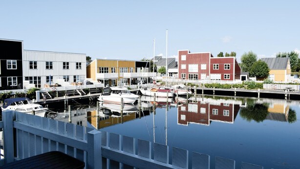 Un puerto deportivo con barcos amarrados, rodeado de edificios con diversos estilos arquitectónicos.