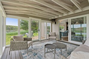 Une terrasse couverte avec un plafond en bois, de grandes portes-fenêtres coulissantes et une vue sur une zone verdoyante.