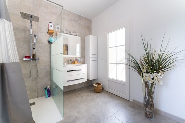 A modern bathroom with a glass shower enclosure, a white vanity, and a large window providing natural light. - Provencal bastide with heated pool near Alpilles and Luberon (Vernègues)
