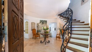 A spacious hallway with a wooden door, a dining area with a table and chairs, and a staircase with a wrought iron railing. - Provencal bastide with heated pool near Alpilles and Luberon (Vernègues)