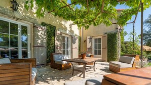 An outdoor patio with wooden furniture, a table, and potted plants. - Provencal bastide with heated pool near Alpilles and Luberon (Vernègues)