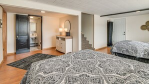 Ein Schlafzimmer mit einem gestreiften Bett, einem Schminktisch, einem Spiegel und einer Treppe zu einem anderen Raum.