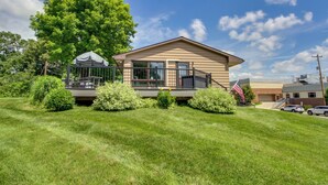 Ein Bungalow mit Balkon, umgeben von gepflegtem Rasen und Bäumen.