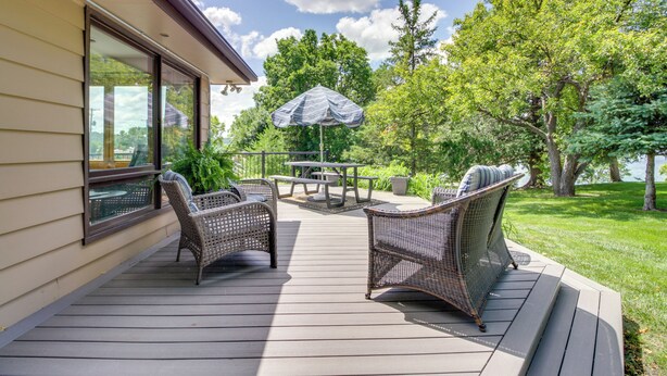Eine Terrasse mit Korbmöbeln, einem Tisch und einem Sonnenschirm.