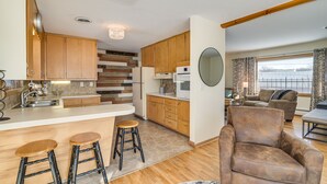 Eine moderne Küche mit Holzschränken, einer zentralen Kochinsel mit Sitzgelegenheiten, einem Kühlschrank und einer Mikrowelle.