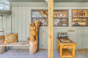 A rustic wooden bench, a wooden table, and a window with a view of the forest.