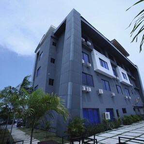A modern building with multiple floors, air conditioning units, and a gated entrance.