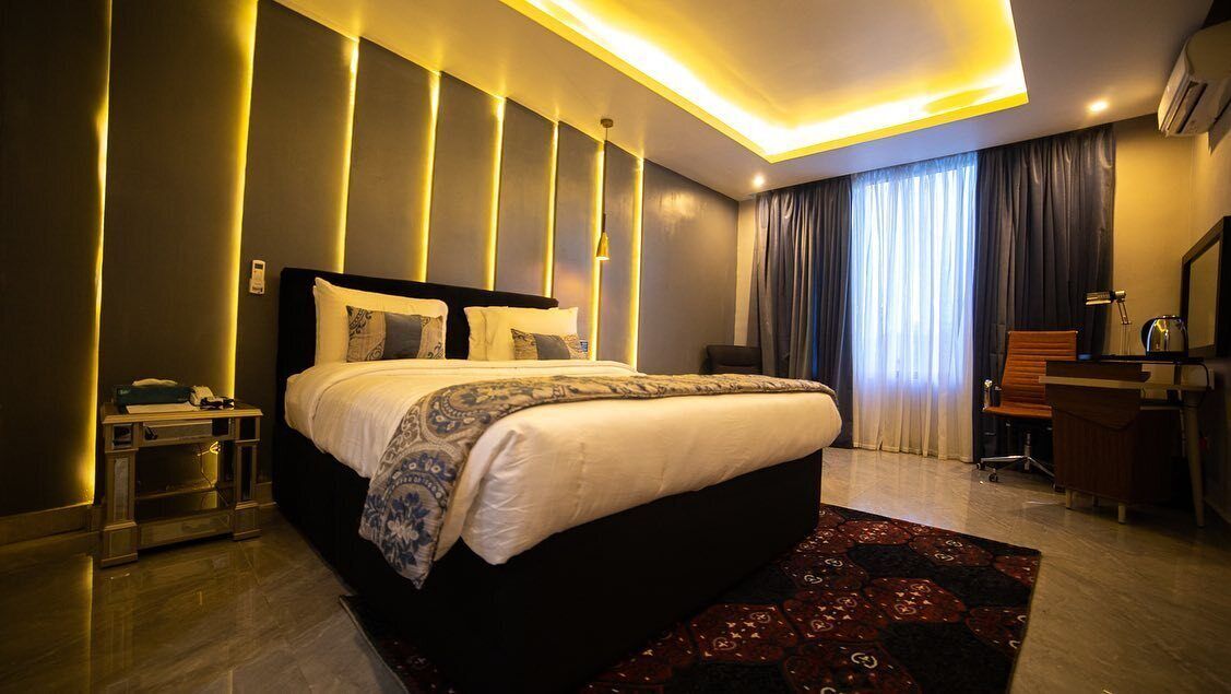 Une chambre d’hôtel moderne avec un grand lit, des tables de chevet, un bureau et une chaise.