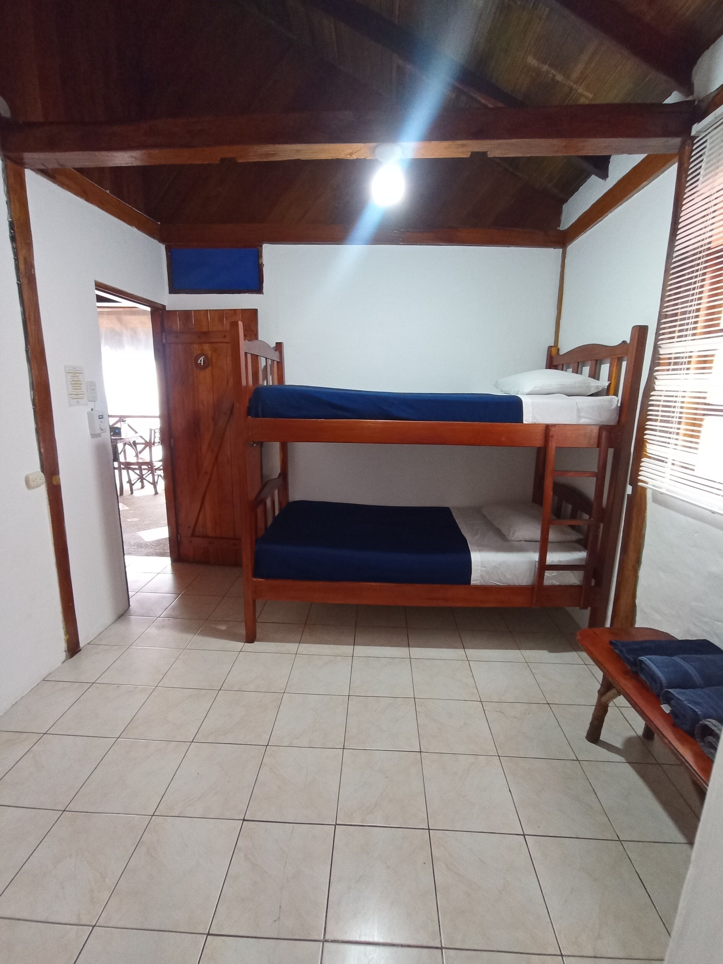 Un dormitorio con literas, una mesita pequeña y una puerta que da a un espacio exterior.