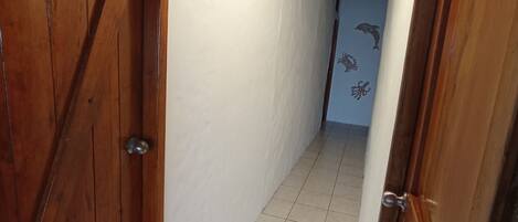 A narrow hallway with wooden doors and white walls.