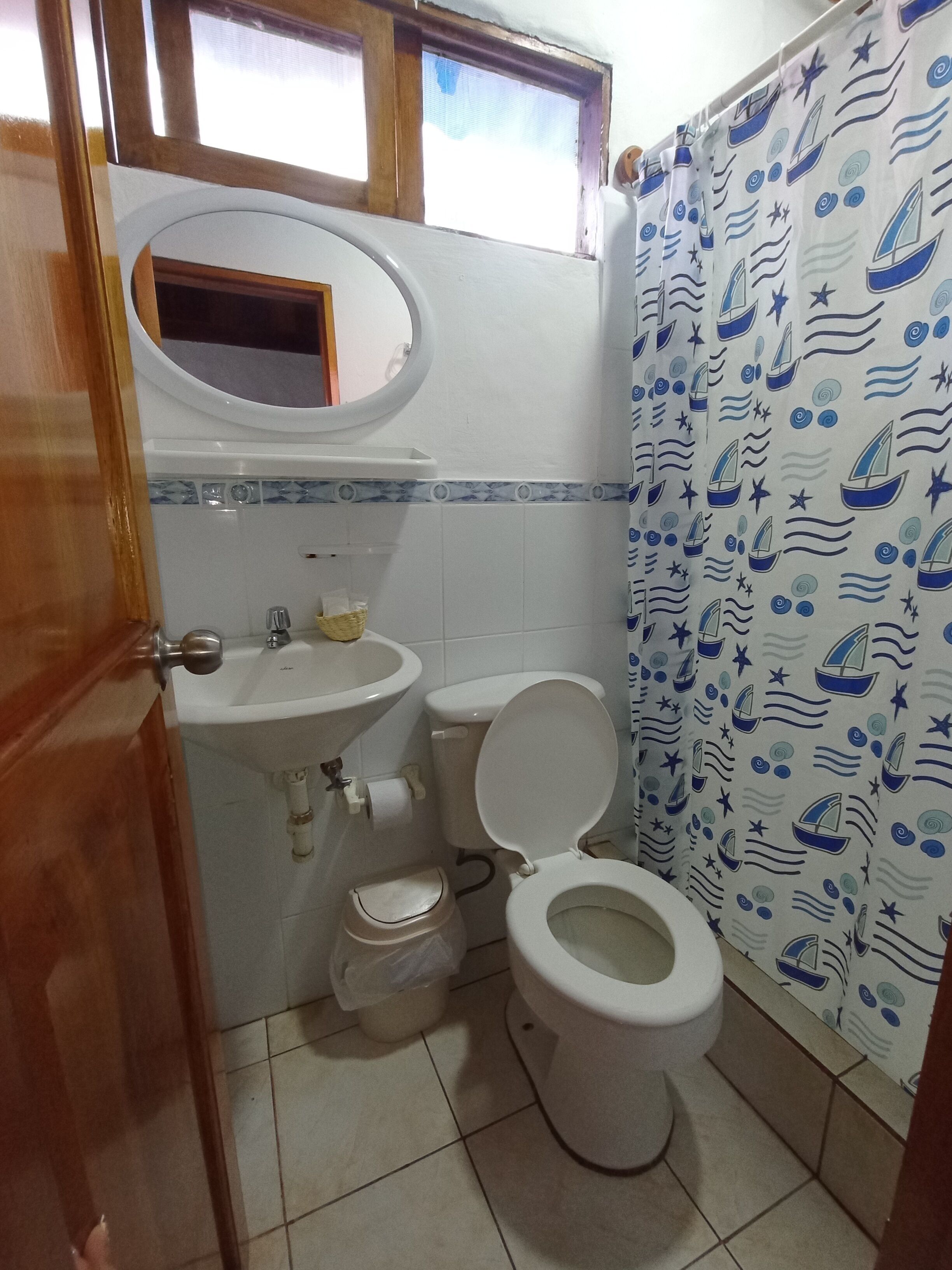A bathroom with a toilet, sink, and a window above the sink.