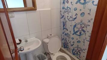 Un baño pequeño con inodoro, lavamanos y cortina de ducha con motivos náuticos.