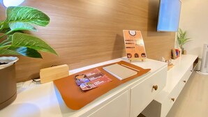 A reception desk with a menu board, a potted plant, and a television mounted on the wall. - Rustic charm meets modern elegance at our wood & white retreat. (Butuan City)