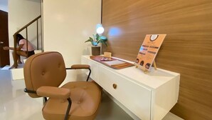 A reception desk with a brown chair, a potted plant, a menu sign, and a staircase in the background. - Rustic charm meets modern elegance at our wood & white retreat. (Butuan City)