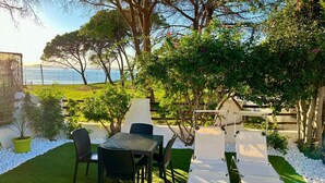 Une terrasse avec une table et des chaises, un fauteuil de relaxation et une vue sur la mer.