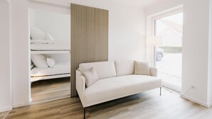 A modern living room with a sofa, a built-in bench, and a large window.