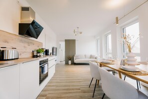 A modern kitchen with white cabinetry, a wooden countertop, and a built-in oven.