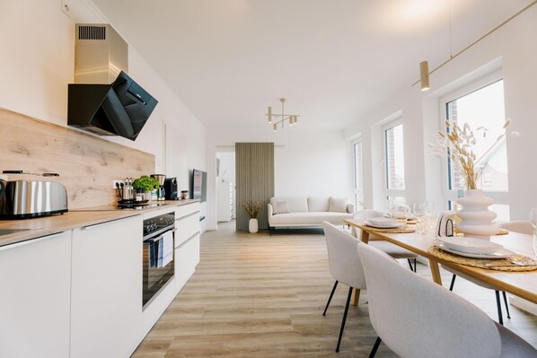 Une cuisine moderne avec des meubles blancs, un plan de travail en bois et un four encastré.