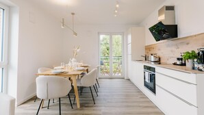 A modern kitchen with a wooden countertop, white cabinets, and a built-in oven. - de See - Suite 4 Seitliche Deichlage (Greetsiel)