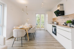 Eine moderne Küche mit Holztischplatte, weißen Schränken und einem eingebauten Backofen.