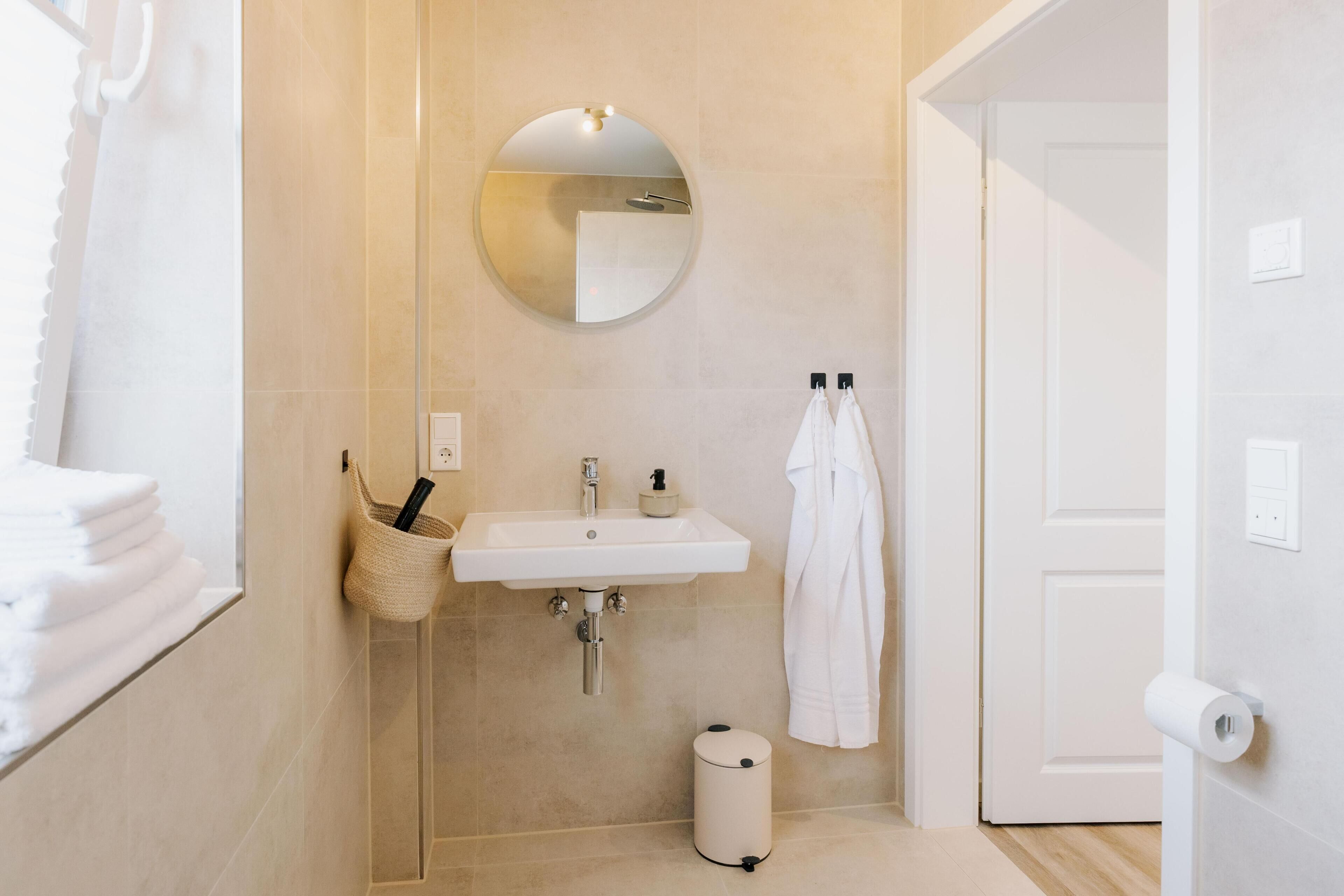 Une salle de bain équipée d’un lavabo, d’un miroir, d’un porte-serviettes et d’un support à papier toilette.