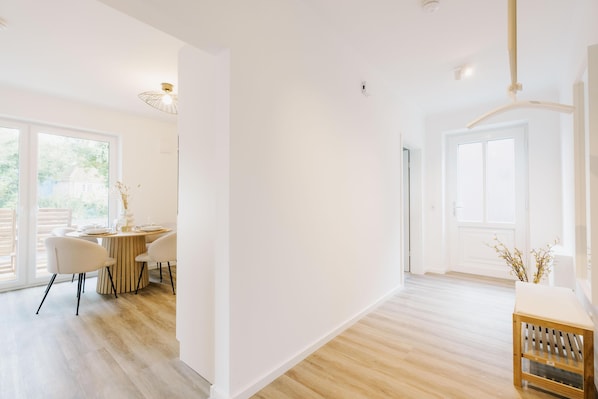 Una habitación amplia con comedor, ventanas grandes y suelo de madera.