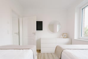 Camera da letto con due letti, una cassettiera, uno specchio e una finestra.