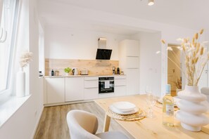 Una cocina moderna con armarios blancos, encimera de madera y horno empotrado.