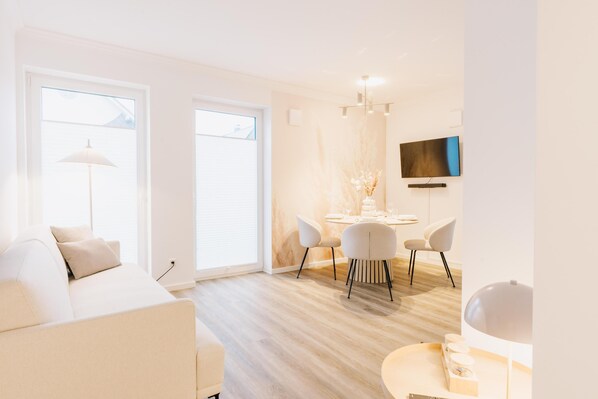 Una sala de estar moderna con sofá, mesa de comedor, sillas y televisor.