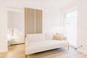 Un salon moderne avec un canapé, une lampe et une fenêtre.