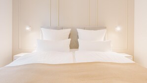 A neatly made bed with white linens and a beige textured blanket, flanked by two bedside tables with lamps. - de Diek - Suite 3 Seitliche Deichlage (Greetsiel)