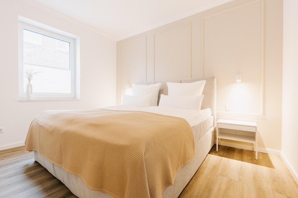 A bedroom with a bed, bedside table, and a window.