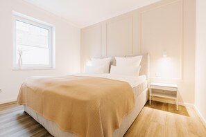Un dormitorio con cama, mesita de noche y ventana.