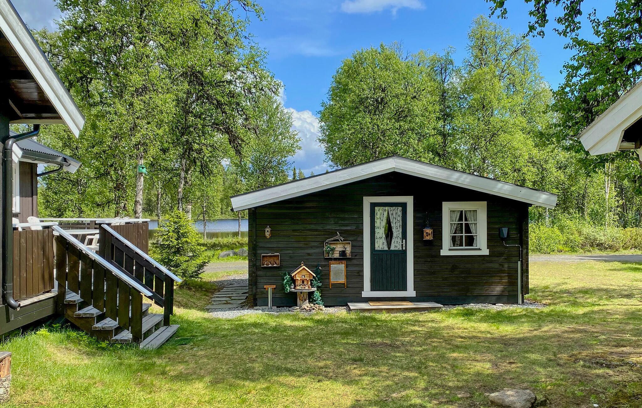 Een klein huisje met een veranda, een klein terras en een vogelhuis.