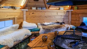 A cozy cabin interior with wooden walls, a fur-covered bench, a table with a grill, and a window with a view. - Nice home in Gol with kitchen (Gol)