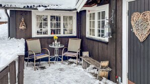 A cozy outdoor seating area with two chairs and a table, surrounded by snow-covered ground and wooden walls. - Nice home in Gol with kitchen (Gol)