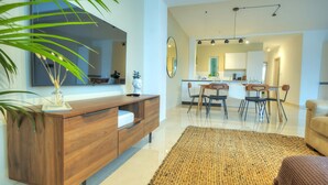 A modern living room with a wooden console, a large mirror, and a dining area with chairs and a table. - Luxury&stylish 2bedroom seafront, balcony GOGZR-4 (Gzira)