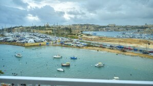 A marina with numerous boats docked, a sandy beach, and a historic building in the background. - Luxury&stylish 2bedroom seafront, balcony GOGZR-4 (Gzira)