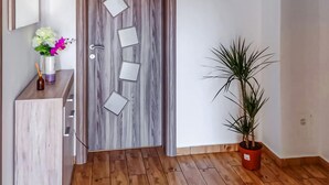 Une porte en bois ornée de motifs géométriques découpés, une plante en pot et une petite table avec des fleurs et une bougie.