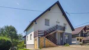 Une maison à deux étages avec un escalier en pierre, un balcon et un ciel dégagé.