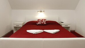 Une chambre d’hôtel avec une couvre-lit rouge, des oreillers blancs et une lampe de chevet.